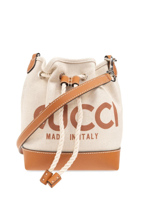 White bucket bag with brown leather strap and Gucci logo.