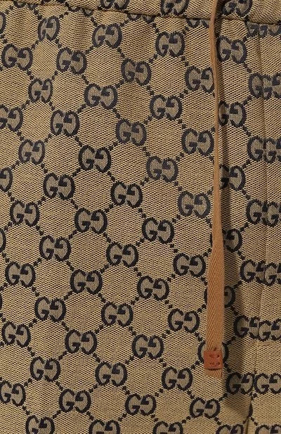 Close-up of a beige fabric with black Gucci logo pattern