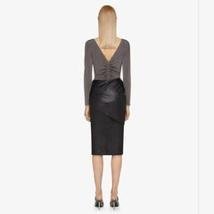 Woman wearing a gray long-sleeve top and black leather skirt on a white background