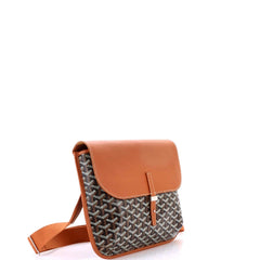 A small crossbody bag with a brown leather top flap and a black and white patterned body, shown against a plain white background.