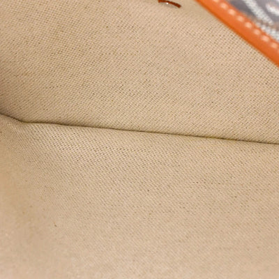 Close-up of a beige woven fabric surface with a visible fold and a small orange edge detail in the upper right.
