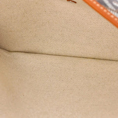 Close-up of a beige woven fabric surface with a visible fold and a small orange edge detail in the upper right.