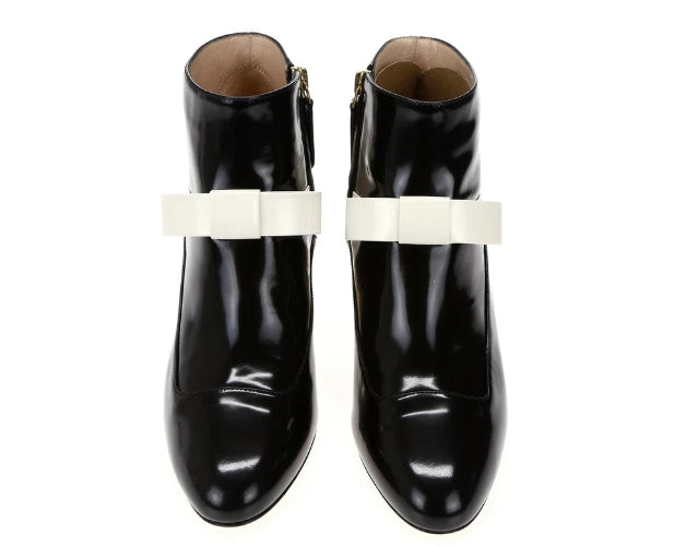 Black shiny boots with white bow-like accessories on a white background