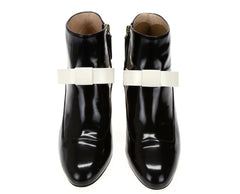 Black shiny boots with white bow-like accessories on a white background