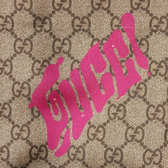 Close-up of Gucci logo with pink text on a patterned background