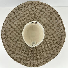A top-down view of a Gucci hat featuring the signature GG monogram canvas in beige and brown, with a cream-colored inner crown.