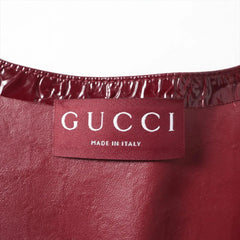 Close-up of a burgundy leather Gucci garment showing the interior waistband with a glossy patent leather trim and a central fabric label reading 'GUCCI MADE IN ITALY'.
