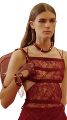 Woman wearing a red dress with a floral pattern, holding a red bag.