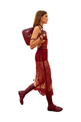 Woman in a red dress with a purple bag on a plain background