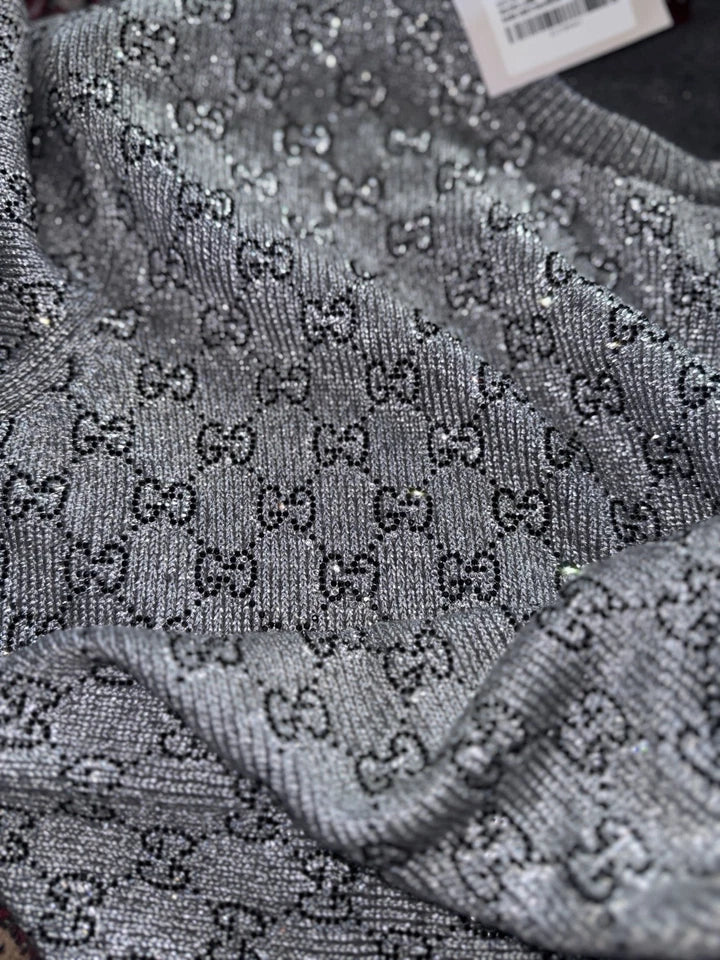 Gray sweater with a pattern of small letters on it.
