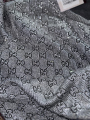 Gray sweater with a pattern of small letters on it.