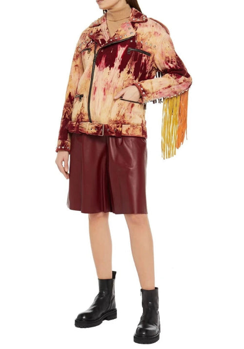 Person wearing a patterned jacket with fringes and leather shorts on a white background