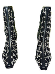 Black high-heeled boots with white pattern on a Gucci branded background