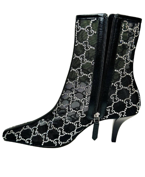 Black high-heeled boots with Gucci logo pattern in front of a Gucci box.