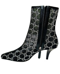 Black high-heeled boots with Gucci logo pattern in front of a Gucci box.