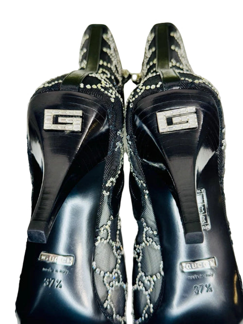 Black high-heeled shoes with decorative elements and Gucci logo on a white background