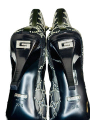 Black high-heeled shoes with decorative elements and Gucci logo on a white background