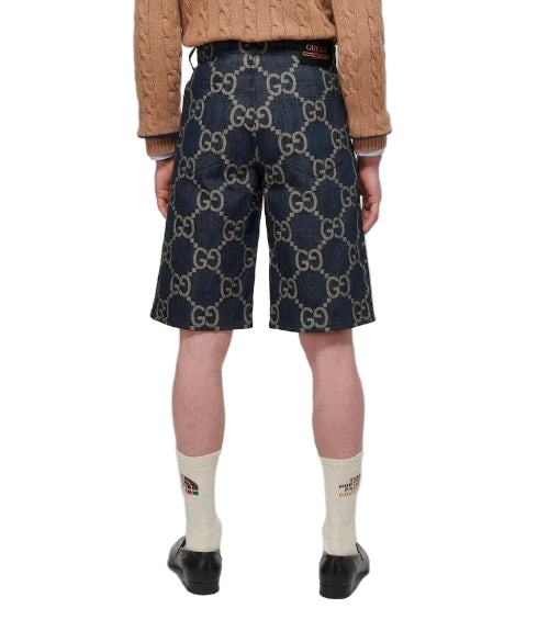Person wearing navy shorts with a pattern, beige sweater, and white socks on a light gray background