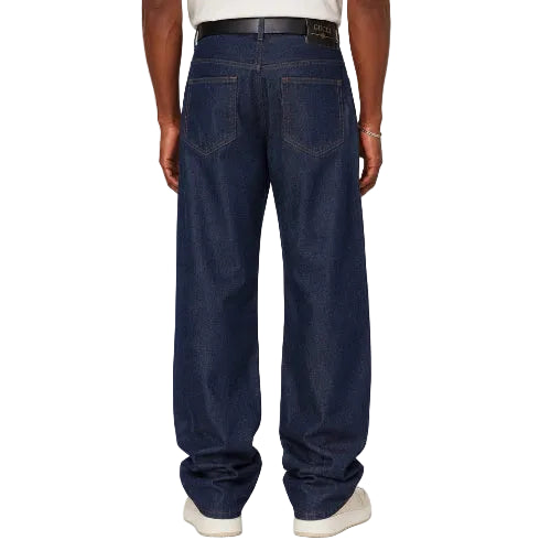 A person shown from the back wearing dark blue wide-leg jeans and white sneakers against a plain light gray studio background.