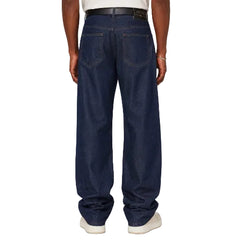 A person shown from the back wearing dark blue wide-leg jeans and white sneakers against a plain light gray studio background.