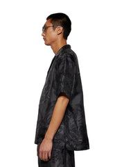 Person wearing a dark patterned shirt against a white background