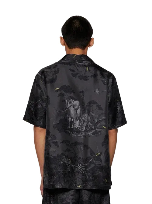 Person wearing a black patterned shirt with an elephant design on a white background