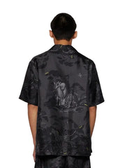 Person wearing a black patterned shirt with an elephant design on a white background
