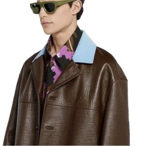 Person wearing a brown leather jacket with a colorful shirt underneath on a white background