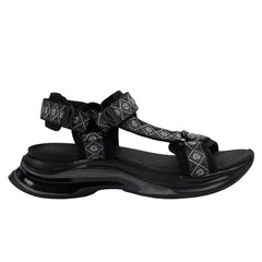 Black sandal with patterned straps on a light gray background