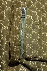 Close-up of a Gucci zippered garment featuring the brand's signature GG monogram pattern in olive green and beige.