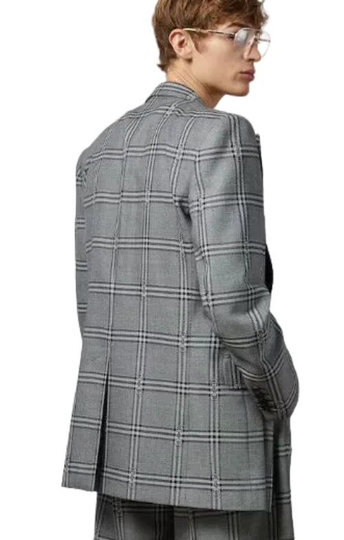 Person wearing a gray checkered blazer on a plain background