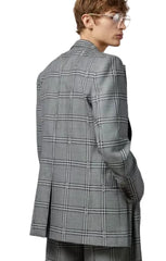 Person wearing a gray checkered blazer on a plain background