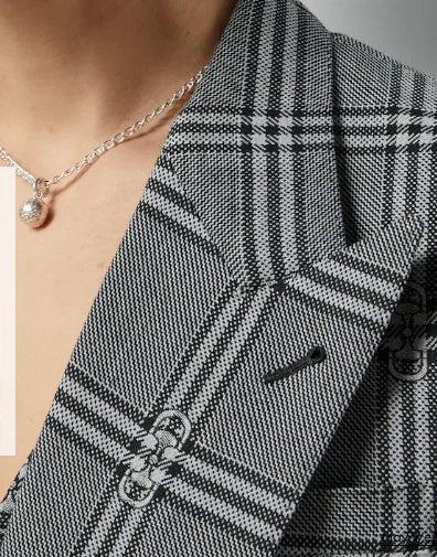 Close-up of a person wearing a black and white checkered blazer with a necklace.