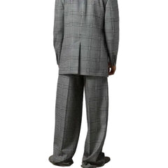 Person wearing a gray plaid suit against a plain background