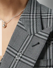 Close-up of a person wearing a black and white checkered blazer with a necklace.