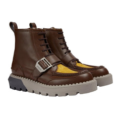 Brown leather boots with a yellow sole on a light gray background