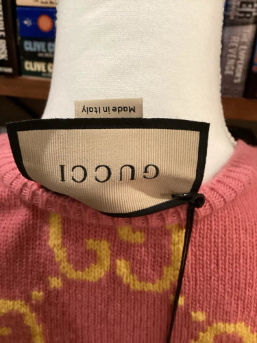 Close-up of a Gucci label on a garment with books in the background