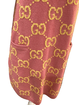 Pink sweater with yellow Gucci logo pattern in a bookstore setting