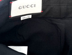 Close-up of the interior waistband of a black Gucci garment, showing the white Gucci brand label stitched onto the inside of the waistband.