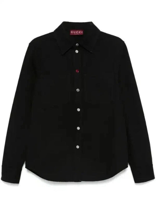 A black Gucci long-sleeve button-up shirt with a pointed collar and a small red Gucci label on the inner neck, displayed against a plain white background.