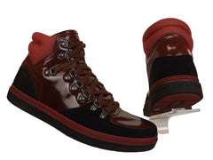 High-top shoes with red and black design on a clear stand against a beige background