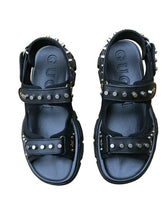 Black studded sandals on a floral-patterned fabric background