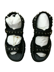 Black studded sandals with white socks on a patterned surface