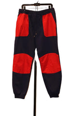 Navy and red jogger pants on a hanger against a neutral wall.
