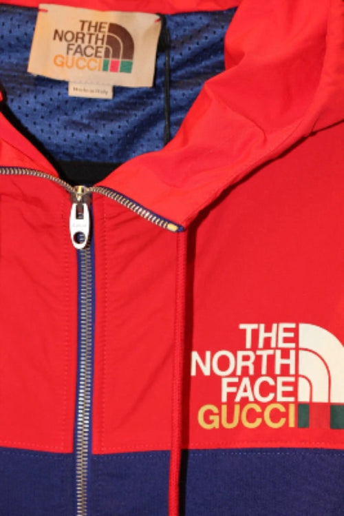 Red and blue jacket with The North Face and Gucci logos on a close-up of the zipper area.