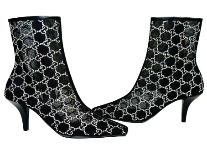 Black high-heeled boots with white pattern on a Gucci branded box.