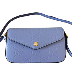 Blue Gucci handbag on a wooden surface with Gucci logo in the background