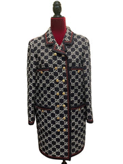 Patterned coat on a mannequin against a white door and green wall.