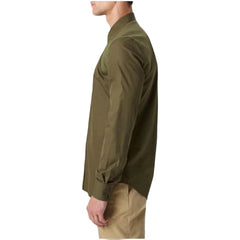 A man shown in side profile wearing an olive green long-sleeve button-up shirt and khaki pants against a light gray studio background.