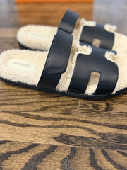Pair of black and beige slippers on a wooden floor